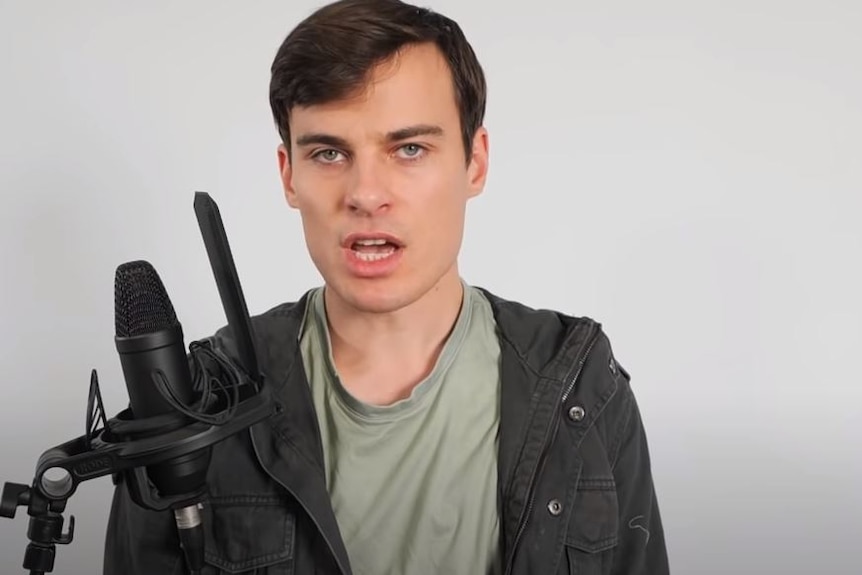 a man speaking in front of a studio mic