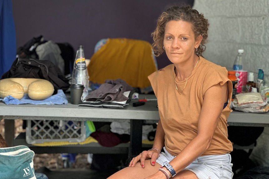 Homeless woman sitting in park shelter with her belongings.