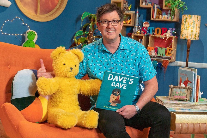 Dave McCormack and Big Ted on the Play School Story Time set. Dave holds the book 'Dave's Cave'.