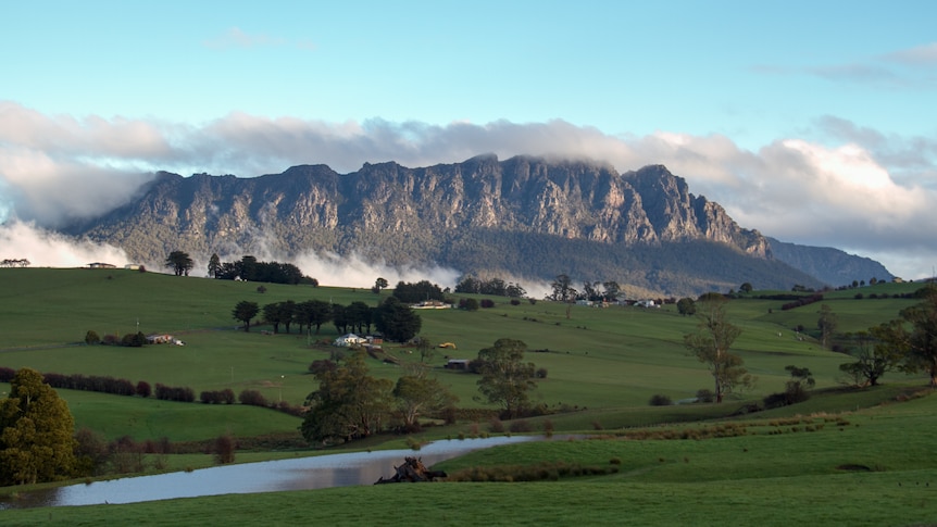 A large mountain looms over pastoral fields