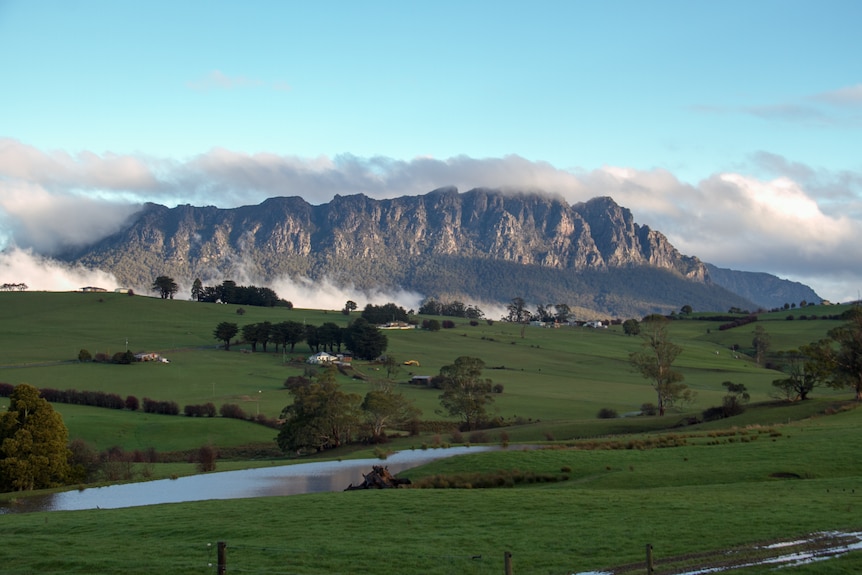 A large mountain looms over pastoral fields