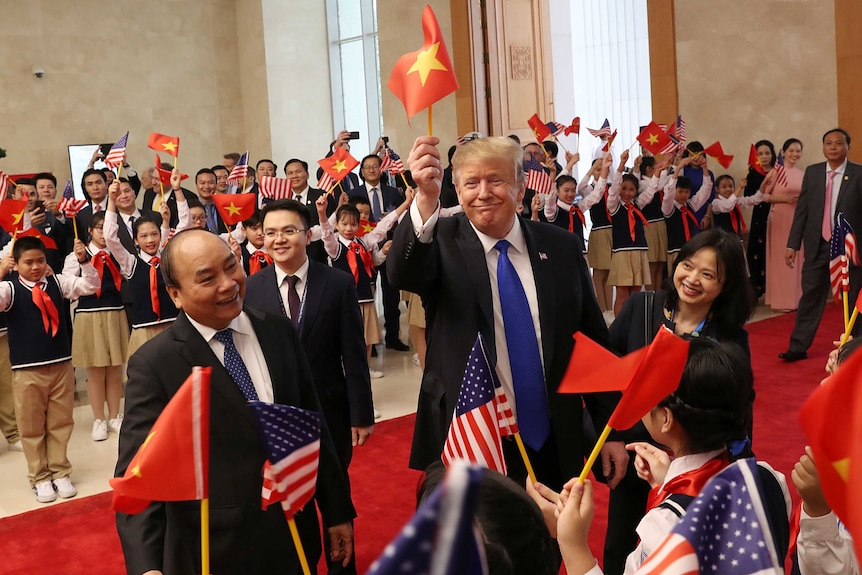 Donald Trump waves a Vietnamese flag as he stands next to his Vietnamese counterpart Nguyen Xuan Phuc.