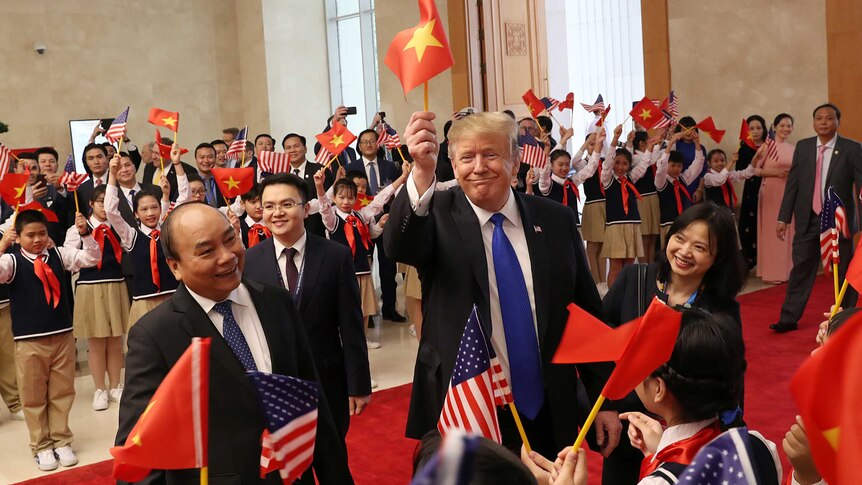 Donald Trump waves a Vietnamese flag as he stands next to his Vietnamese counterpart Nguyen Xuan Phuc.