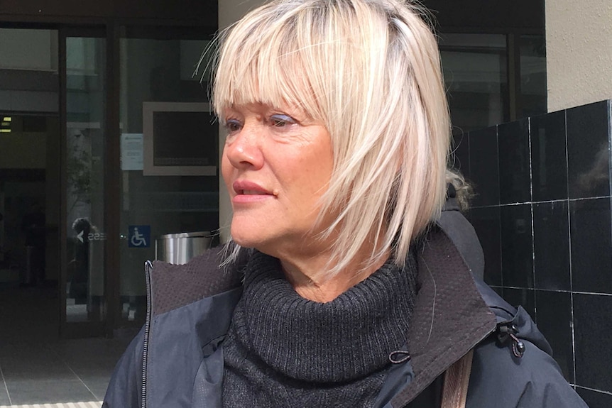 A tight head and shoulders shot of Jane Bache standing outdoors talking.