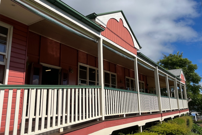 an old wooden building painted pink with a balcony