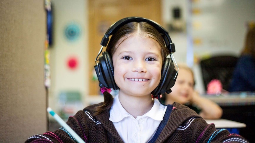A student smiles wearing headphones