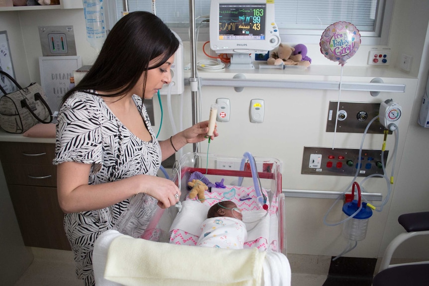 Rachel Cauci feeds her daughter Kyra through a small tube in the neonatal intensive care unit.