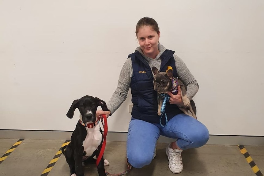 A smiling young woman with two dogs.