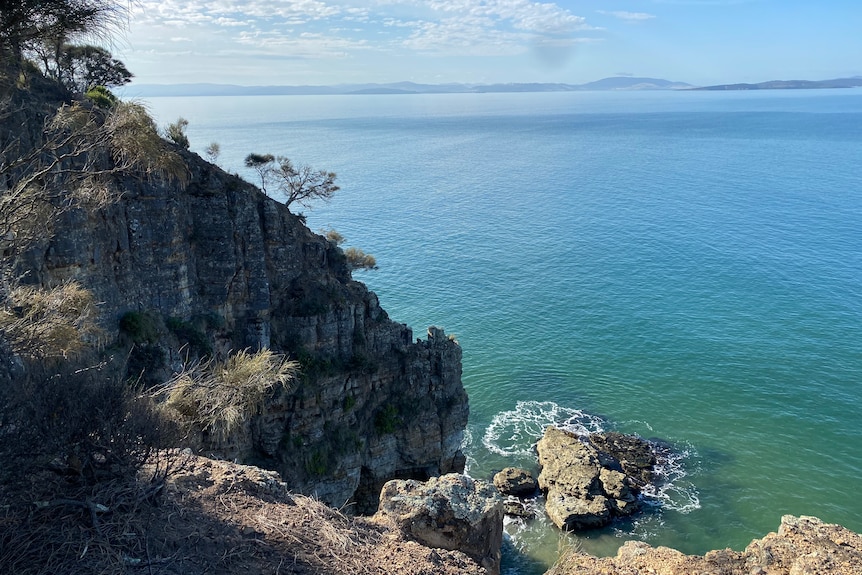 A coastal cliff falling into a blue sea
