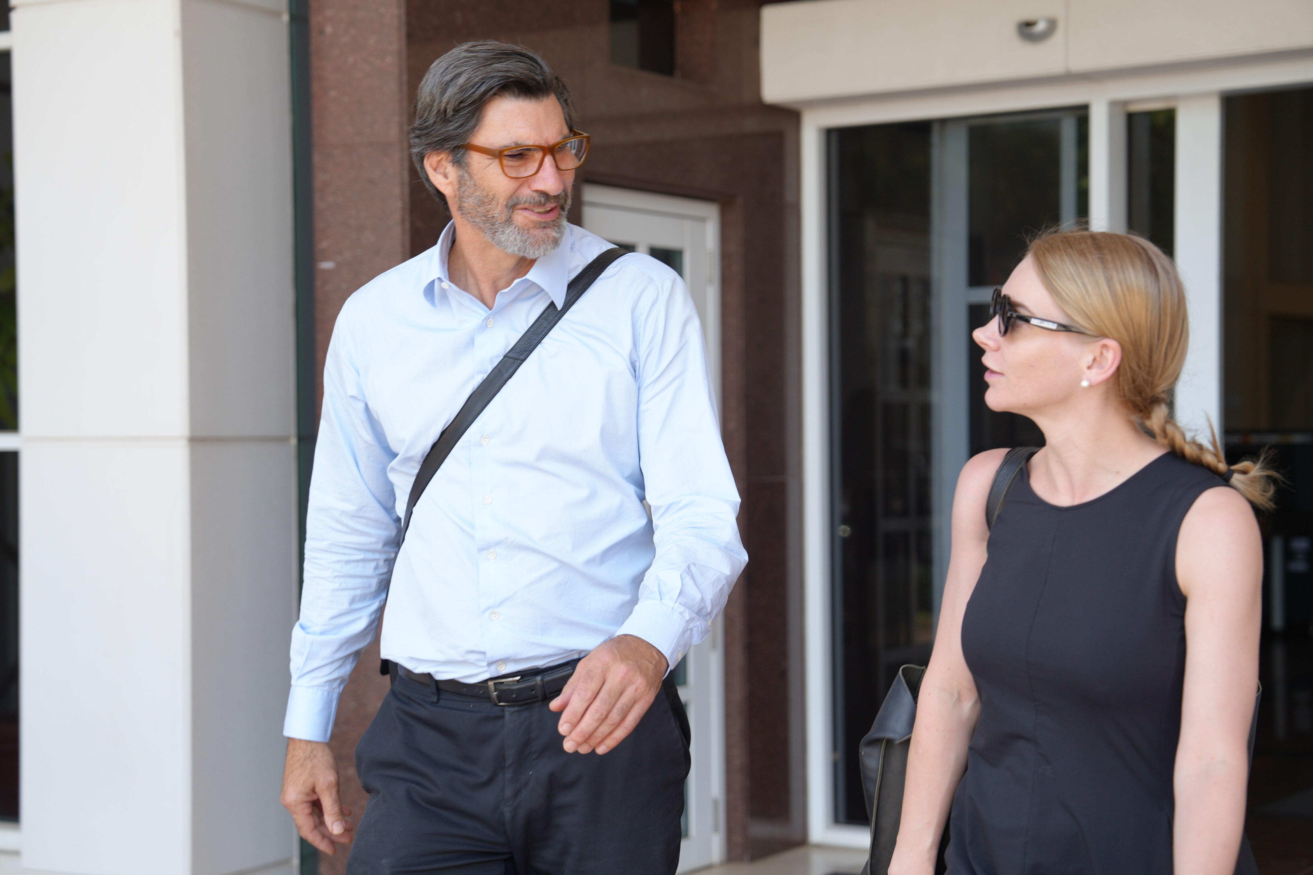 Un hombre con camisa y gafas sale del juzgado.