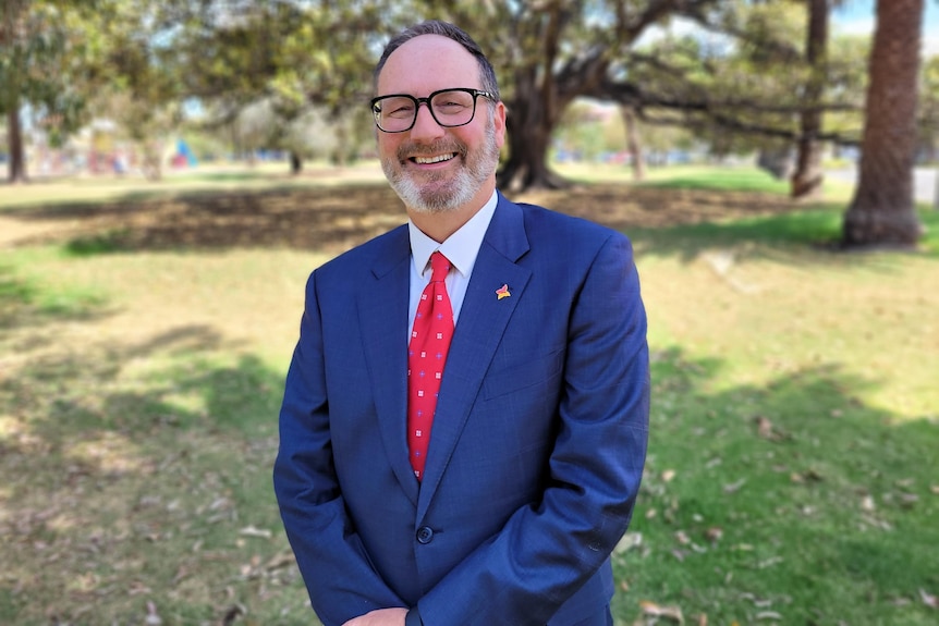 Man with glasses and blue suit in park