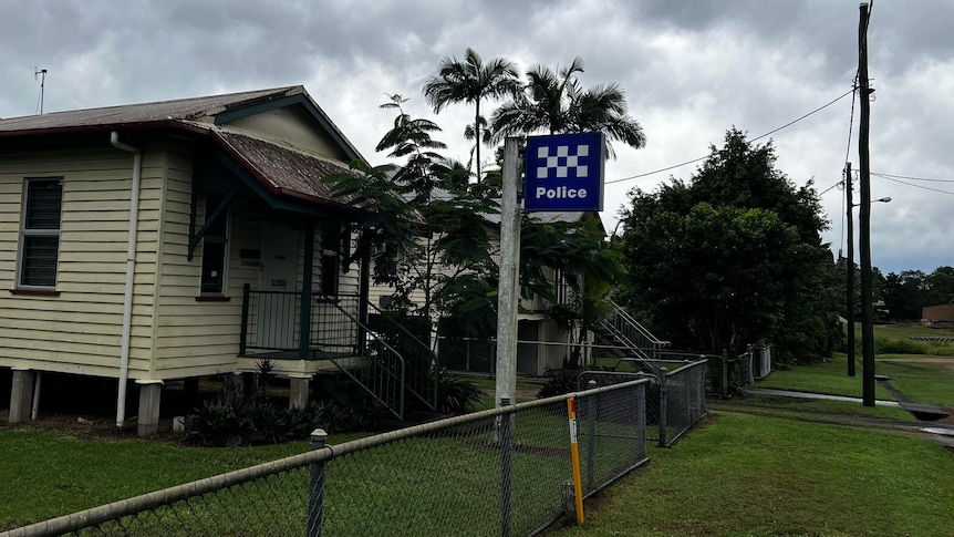 An old, small weatherboard house with a blue and white police sign out the front. 