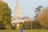 Russian flag hangs off the scaffolding on the Salisbury Cathedral while two children look at it from a park.