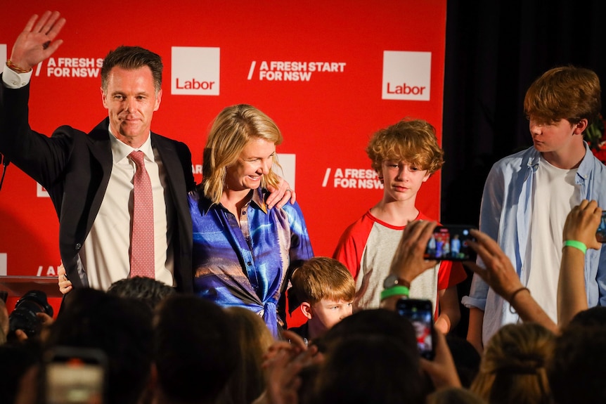nsw premier chris minns celebrates election night on stage with his wife and three sons at a labor supporters hall in 2023
