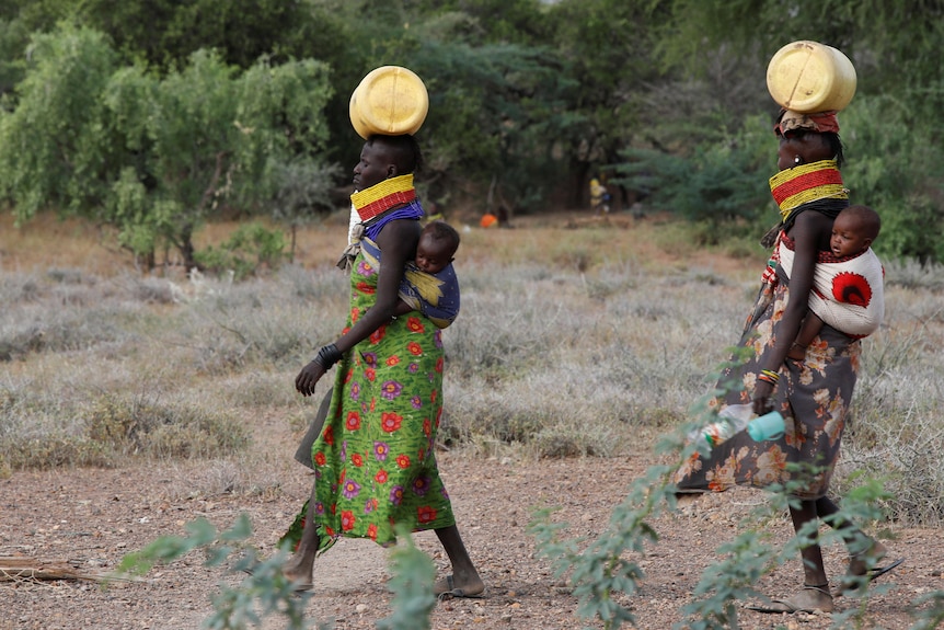 Kenyan women carry their children and containers of water on their heads