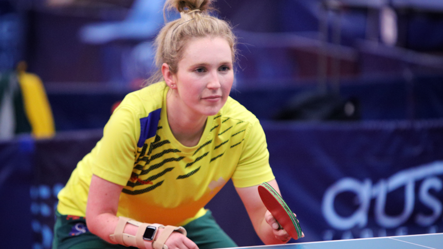 Milly Tapper crouches down at the table tennis table after returning a serve.