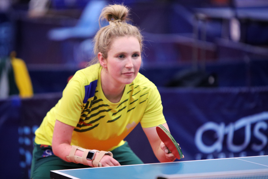 Milly Tapper crouches down at the table tennis table after returning a serve.