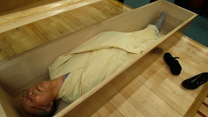 A man lies in a coffin at a South Korean coffin academy, which aims to help prevent suicide. July 4, 2011.