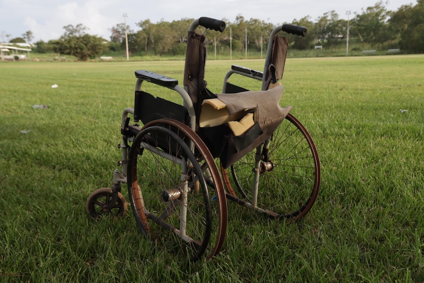 A deteriorated wheelchair sits on the grass of a footy oval in Nhulunbuy.