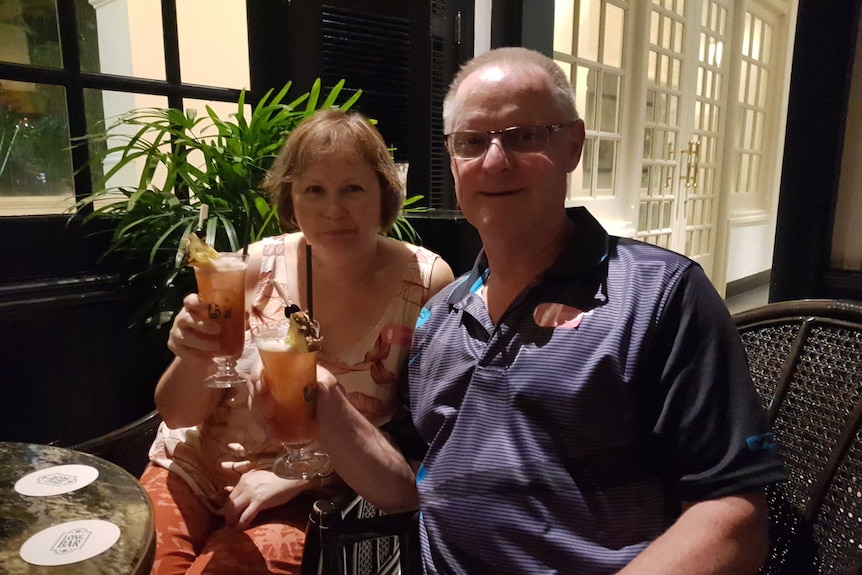 Julie and Michael Schulz sitting at a table with drinks, smiling at camera