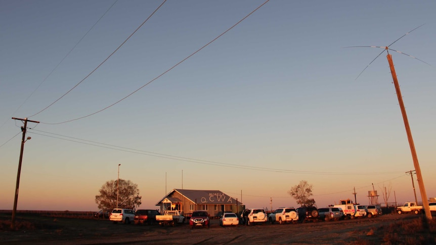 A small hall in a remote landscape with cars in the carpark.