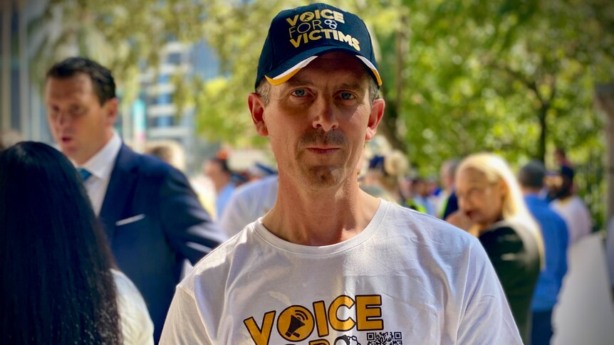 Lee Lovell wearing a hat and shirt that reads 'voice for victims'