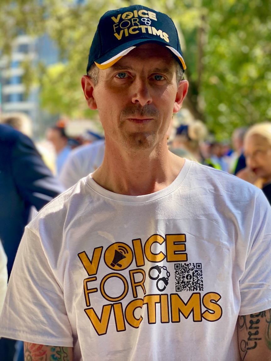 Lee Lovell wearing a hat and shirt that reads 'voice for victims'