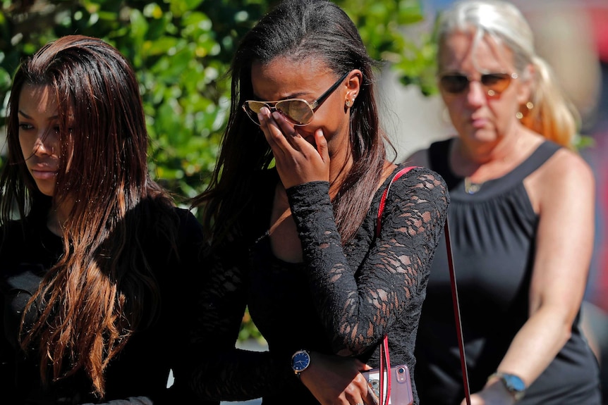 Mourners appear overwhelemed with saddness as they leave a funeral