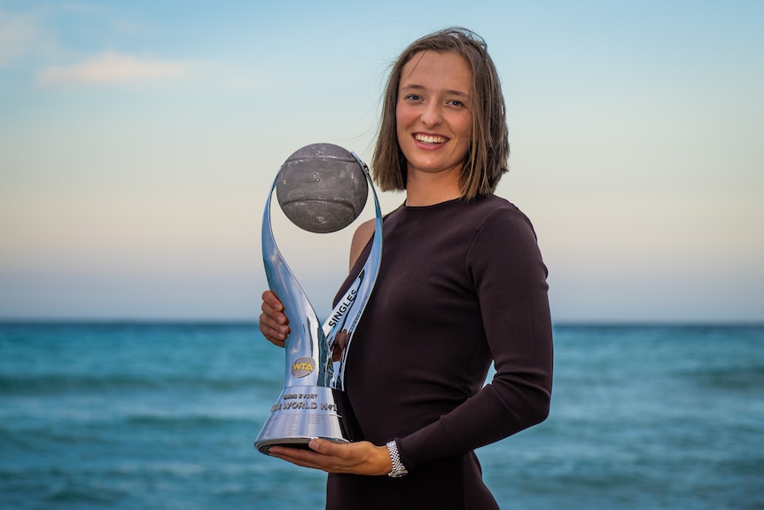 Iga Swiatek poses with a trophy on Hollywood Beach.