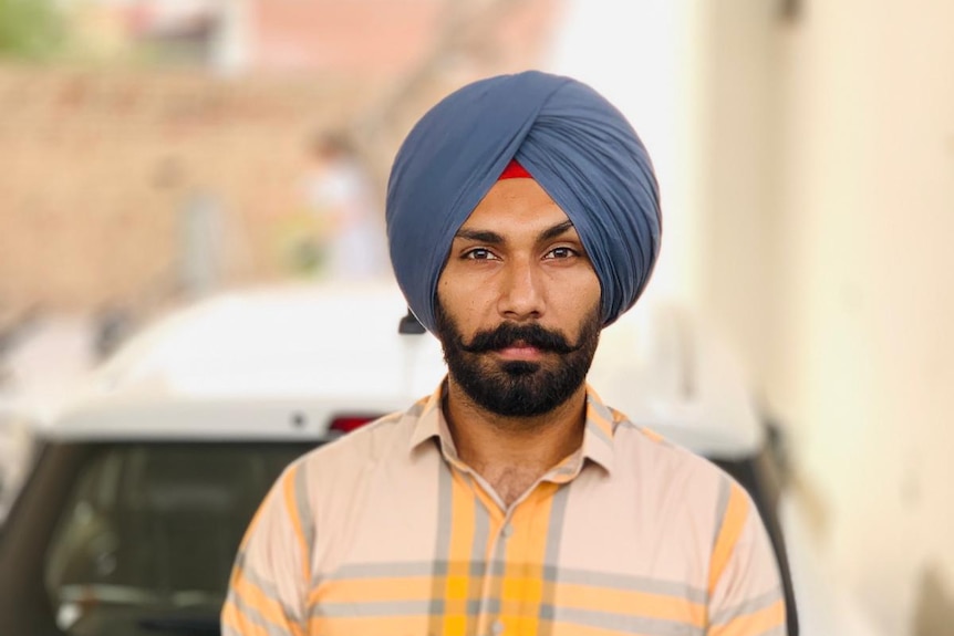 A picture of an Indian man in a blue turban and with a dark beard. 