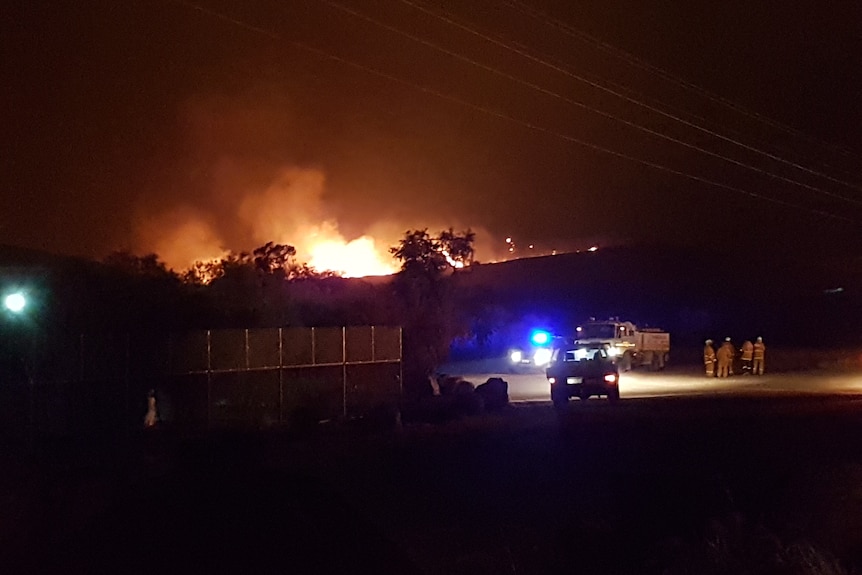 CFS workers standing near an emergency truck at night while a fire rages on