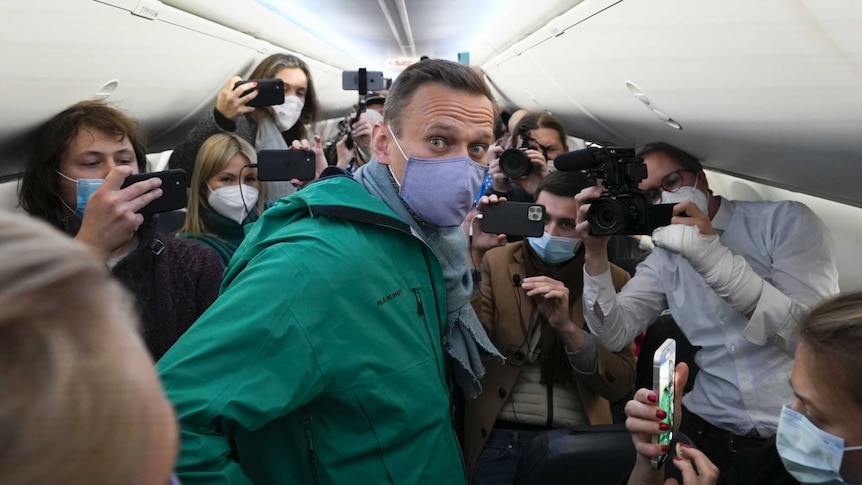 Alexei Navalny is surrounded by journalists inside the plane prior to his flight to Moscow.