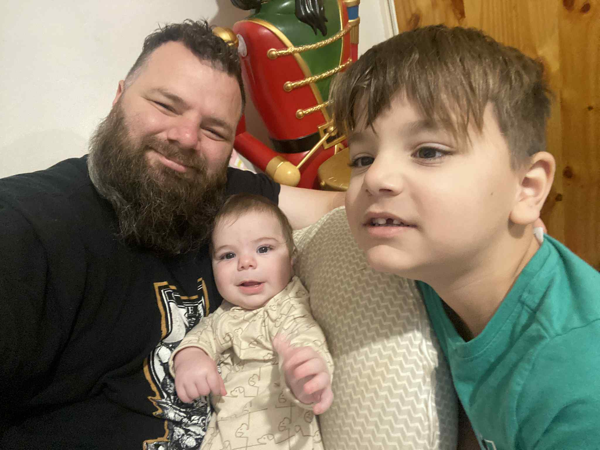 A man sitting on a couch with a baby and his son