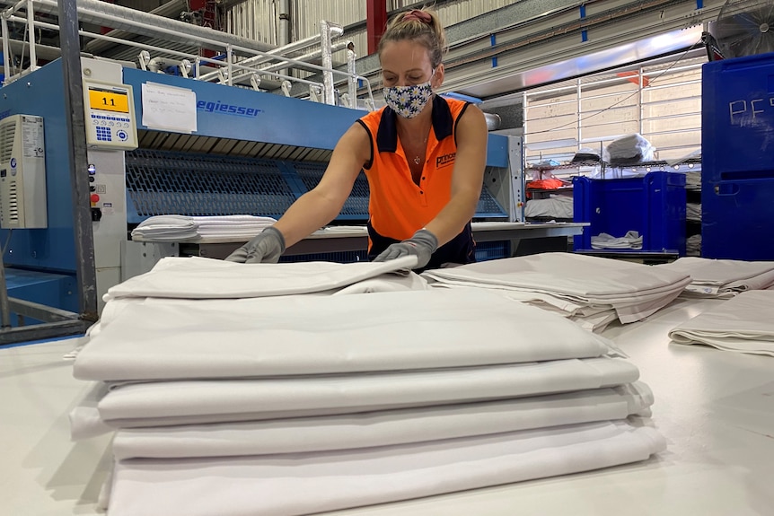 une femme plie des draps dans une usine