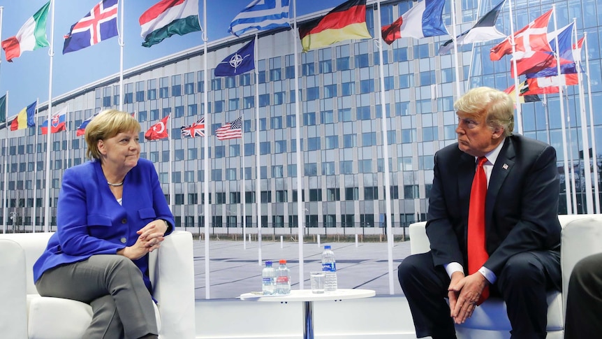 Angela Merkel and Donald Trump are seated next each other looking in different directions