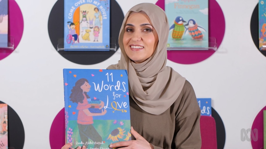Miss Obayda holds up a story book