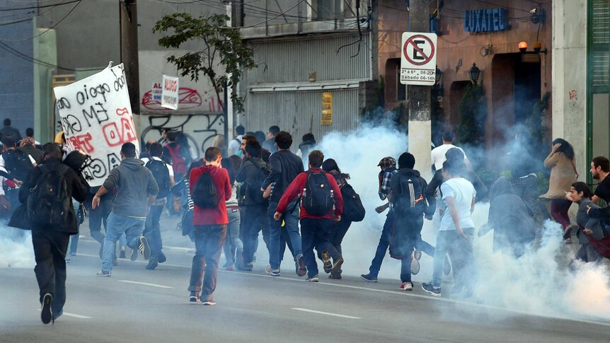 Protesters run after police fire tear gas in Sao Paulo
