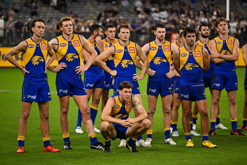 A number of Eagles players stand together looking sad in a post-game presentation