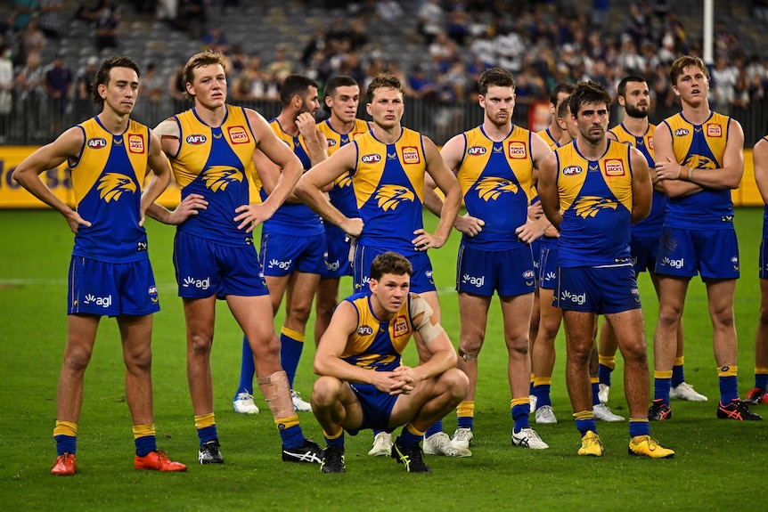 A number of Eagles players stand together looking sad in a post-game presentation