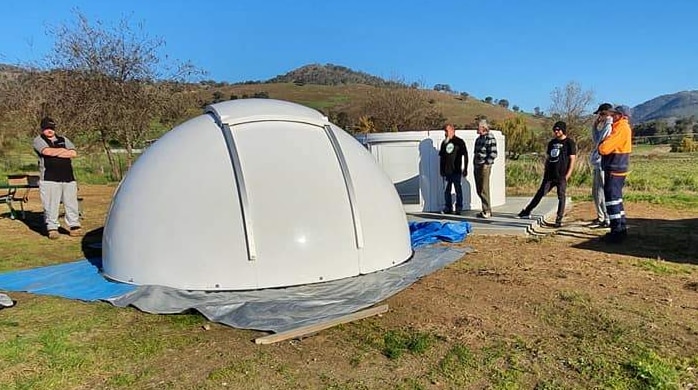white dome observatory in paddock surrounded by men