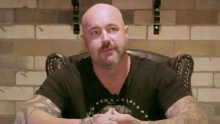 A bald man wearing a black T-shirt