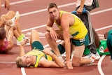 Ash Moloney lies on the ground with Cedric Dubler kneeling on the track over him after the decathlon.