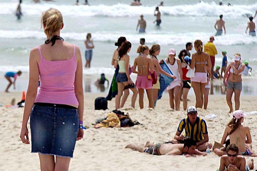 A beach scene with young people and a woman in a denim skirt