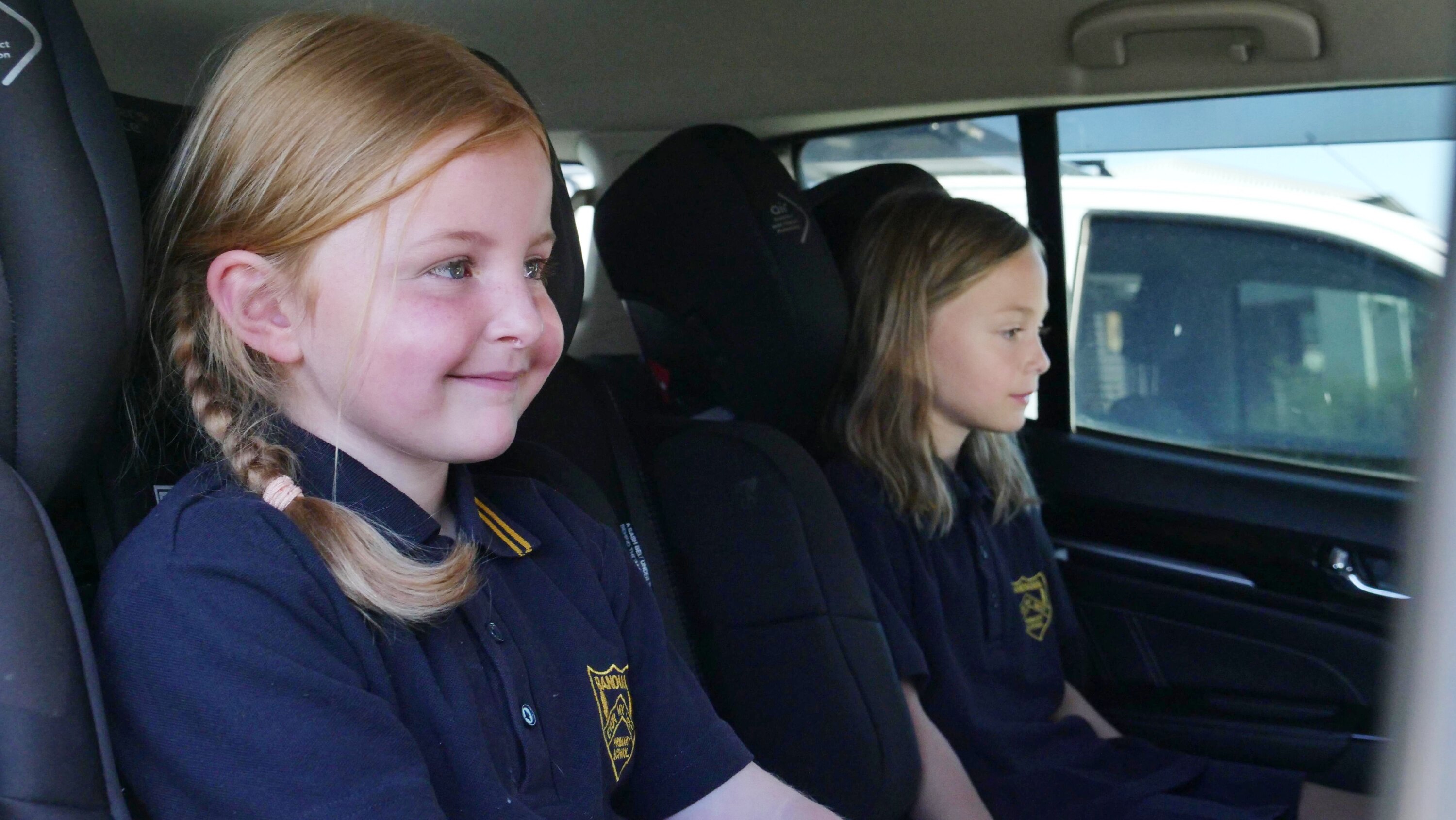 Two young girls sit in a car