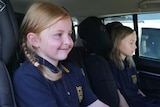 Two young girls sit in a car