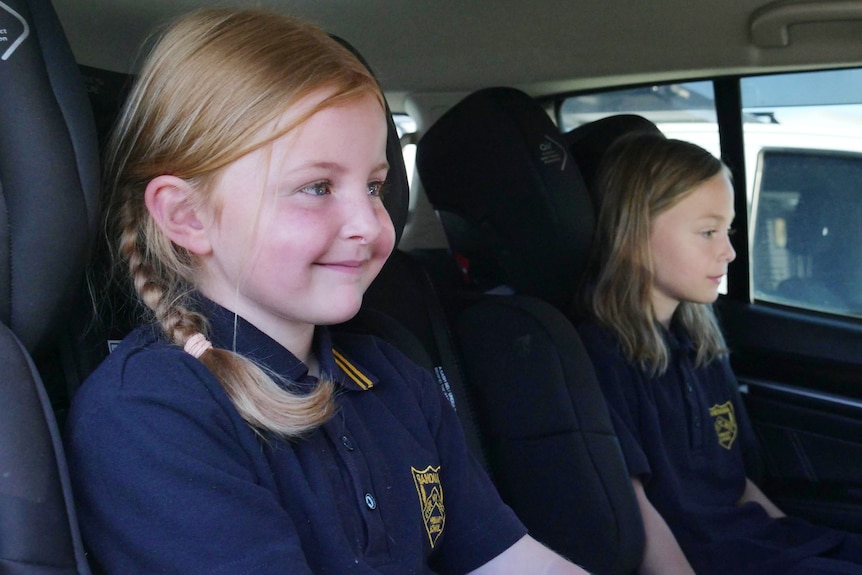 Two young girls sit in a car