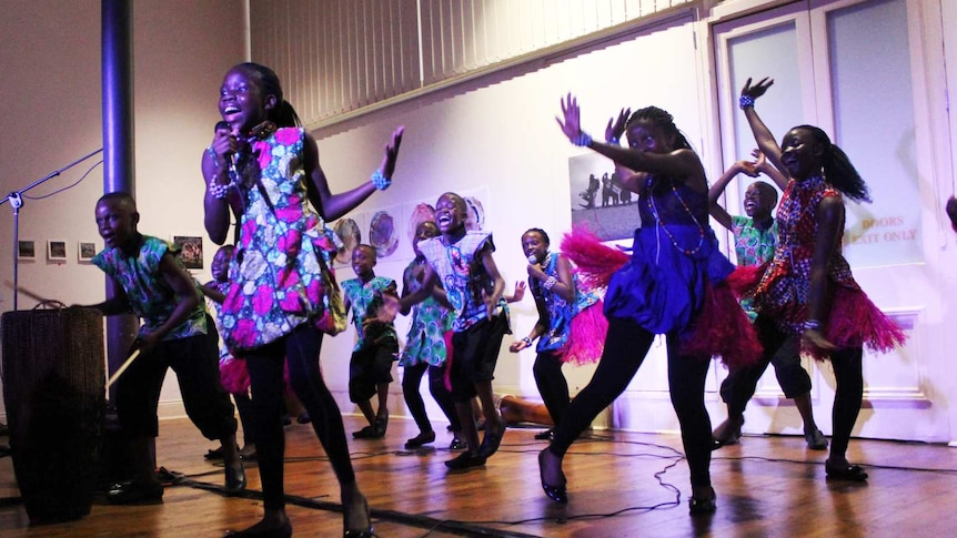 African children dance and sing in colourful outfits.