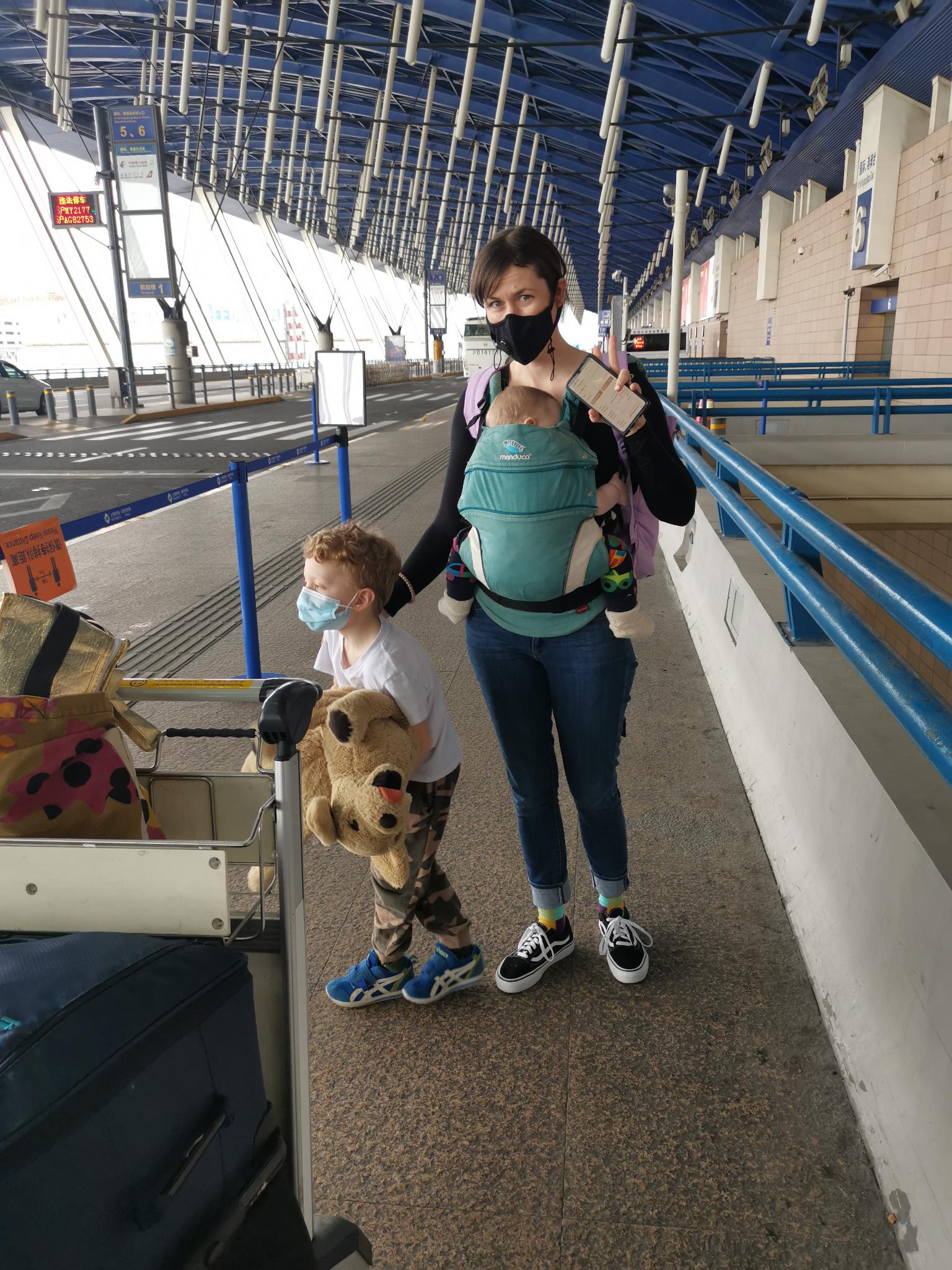 一名妇女带着她的两个孩子站在机场外。