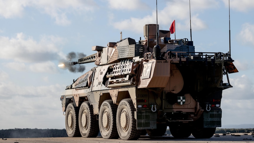 An armoured vehicle fires away from the camera