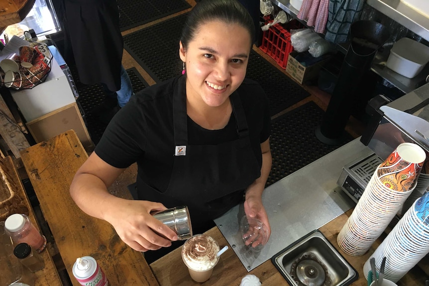 Daniela Ochoa smiles at the camera as she makes a coffee.